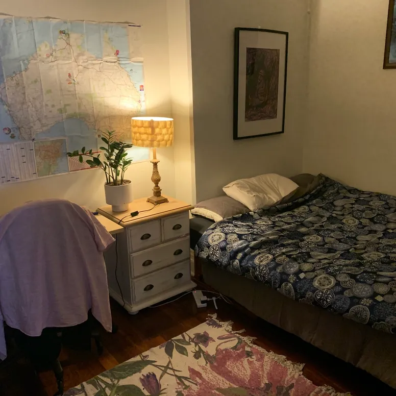 A small room with a bed and a modest desk and nightstand
